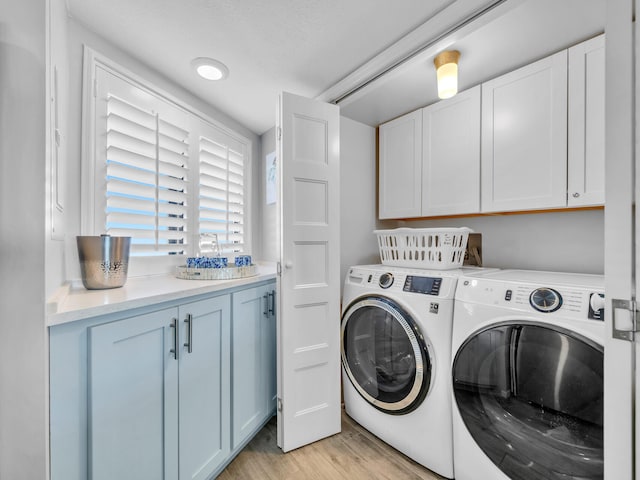 laundry room featuring a sink, cabinet space, light wood-style floors, and washer and dryer