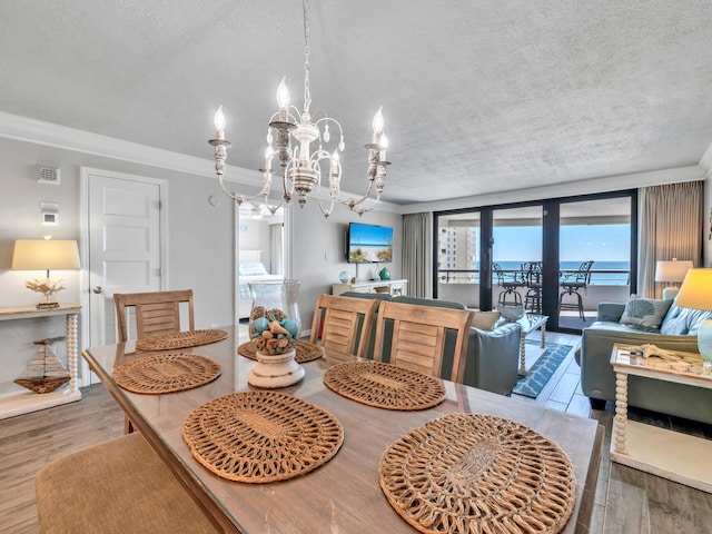 dining area with a textured ceiling, ornamental molding, wood finished floors, and a notable chandelier