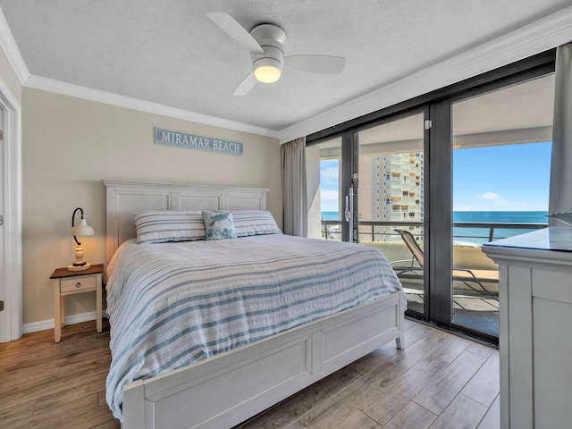 bedroom featuring access to outside, ornamental molding, light wood-style flooring, and a textured ceiling