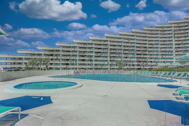 view of swimming pool featuring a view of city, a patio area, and a hot tub