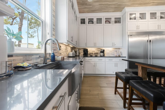 11 Wadleigh Way, Miramar Beach, FL 32550 - kitchen featuring glass insert cabinets, stainless steel built in fridge, backsplash, and white cabinetry