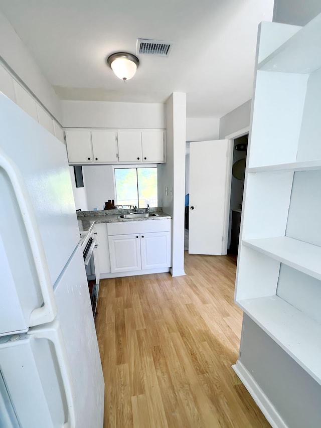 kitchen with range with electric cooktop, sink, white refrigerator, light hardwood / wood-style flooring, and white cabinets