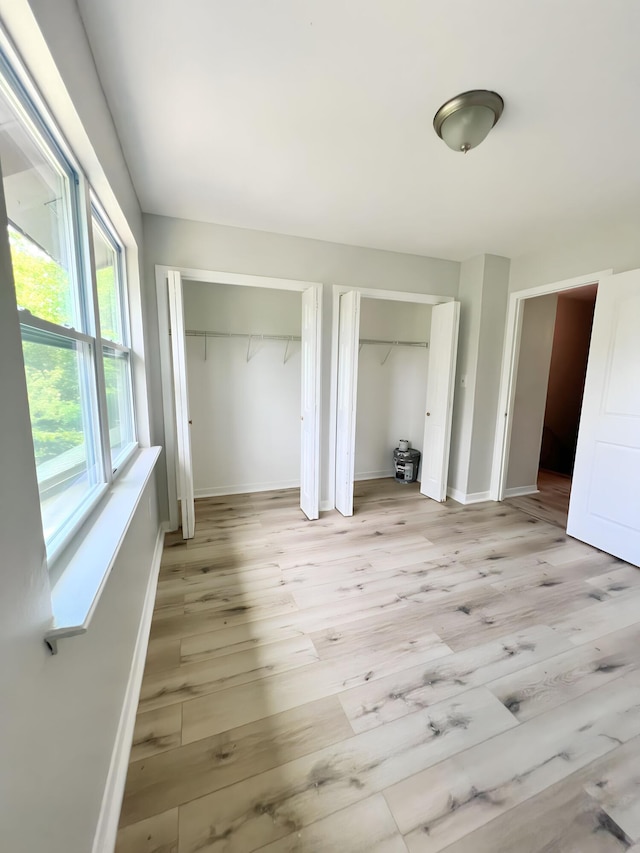 unfurnished bedroom featuring two closets and light hardwood / wood-style floors