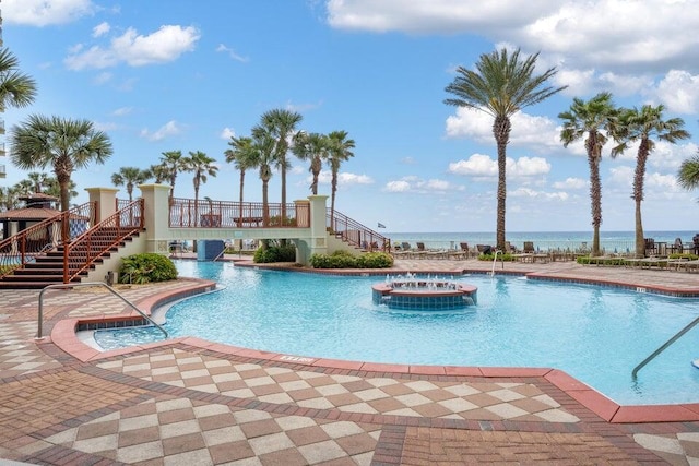 view of pool featuring central AC, a patio area, a jacuzzi, and a water view