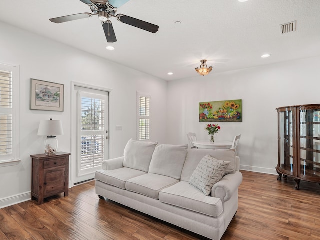 living room featuring ceiling fan and dark hardwood / wood-style flooring