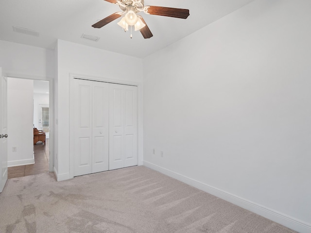 unfurnished bedroom featuring light carpet, a closet, and ceiling fan