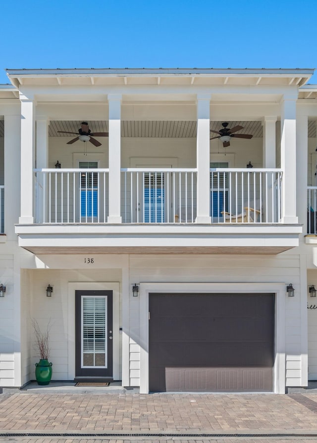 exterior space with ceiling fan, a garage, and a balcony