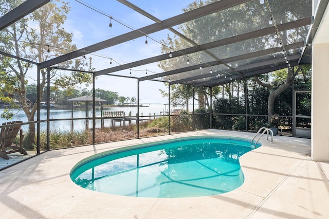 view of swimming pool featuring a patio area, glass enclosure, and a water view