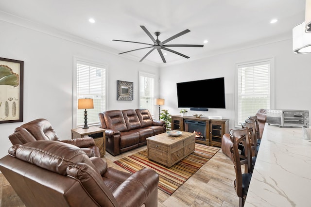 living room featuring crown molding, a healthy amount of sunlight, ceiling fan, and light hardwood / wood-style floors