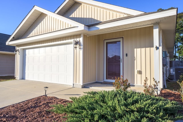 view of front of home with board and batten siding, driveway, an attached garage, and central AC unit