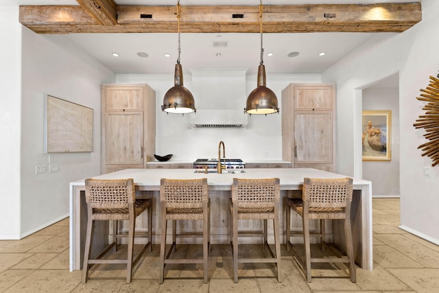 kitchen with pendant lighting, an island with sink, and light brown cabinetry