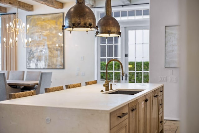 kitchen with light brown cabinetry, sink, a center island with sink, an inviting chandelier, and a breakfast bar area