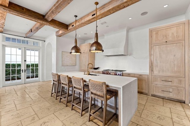 kitchen with pendant lighting, light brown cabinets, french doors, sink, and extractor fan