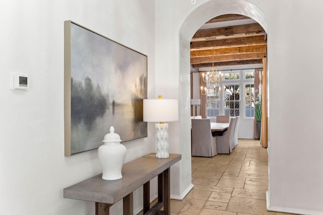 hall featuring beamed ceiling and a notable chandelier