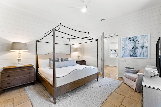 bedroom featuring ceiling fan and wood walls