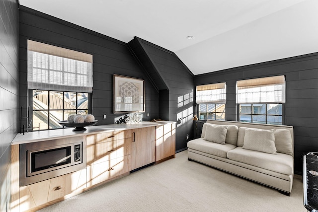 carpeted living room featuring vaulted ceiling and wood walls