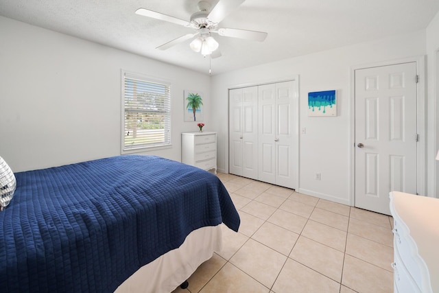 bedroom featuring ceiling fan, a closet, light tile patterned flooring, and a textured ceiling