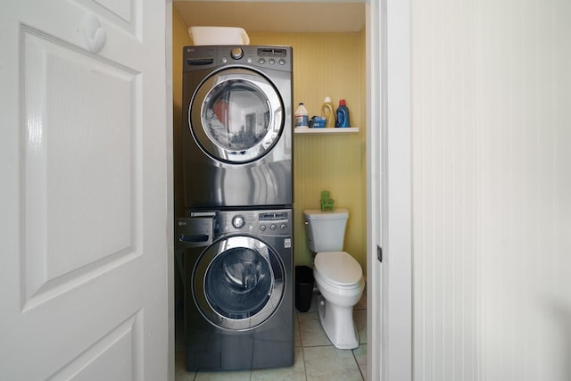 clothes washing area with light tile patterned floors and stacked washer and clothes dryer