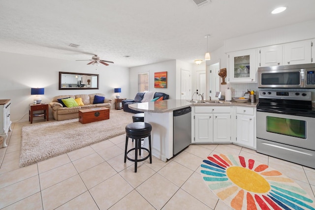 kitchen with ceiling fan, white cabinetry, a breakfast bar area, and appliances with stainless steel finishes