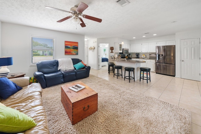 living room featuring ceiling fan, light tile patterned floors, and a textured ceiling