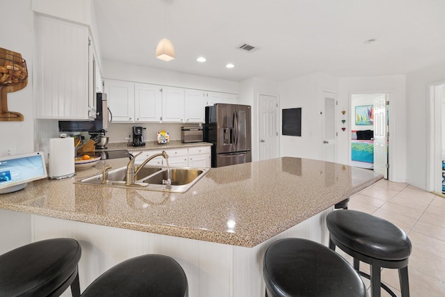 kitchen with pendant lighting, range, sink, kitchen peninsula, and stainless steel fridge with ice dispenser