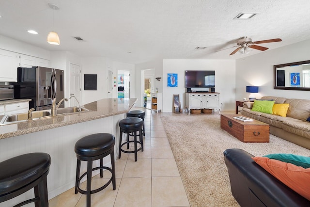 tiled living room featuring ceiling fan, sink, and a textured ceiling