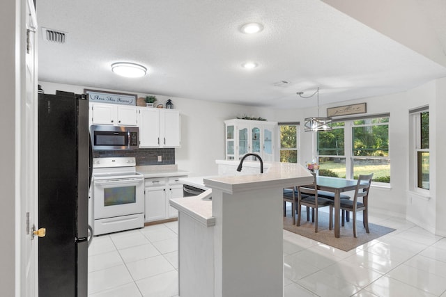 kitchen featuring white cabinets, appliances with stainless steel finishes, light tile patterned flooring, and backsplash