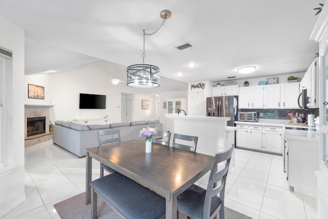 dining space with lofted ceiling, a fireplace, a chandelier, and light tile patterned floors