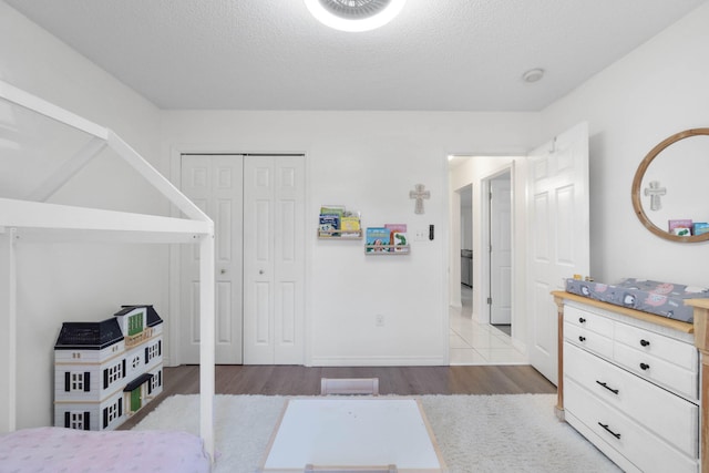 bedroom with a textured ceiling, light hardwood / wood-style flooring, and a closet