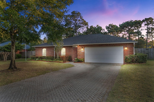 ranch-style house with a garage and a lawn