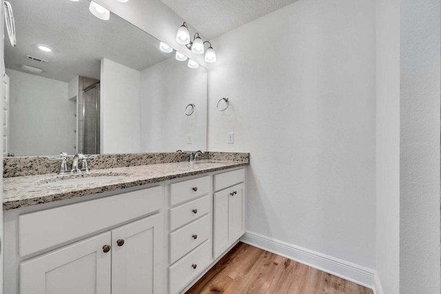 bathroom with hardwood / wood-style flooring, vanity, and a textured ceiling