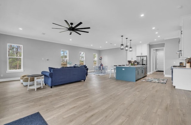 living room featuring ornamental molding, light hardwood / wood-style floors, ceiling fan, and a healthy amount of sunlight