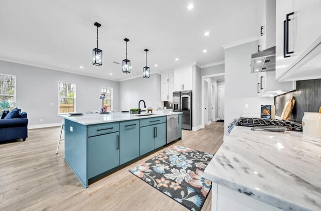 kitchen with pendant lighting, ventilation hood, an island with sink, appliances with stainless steel finishes, and white cabinetry