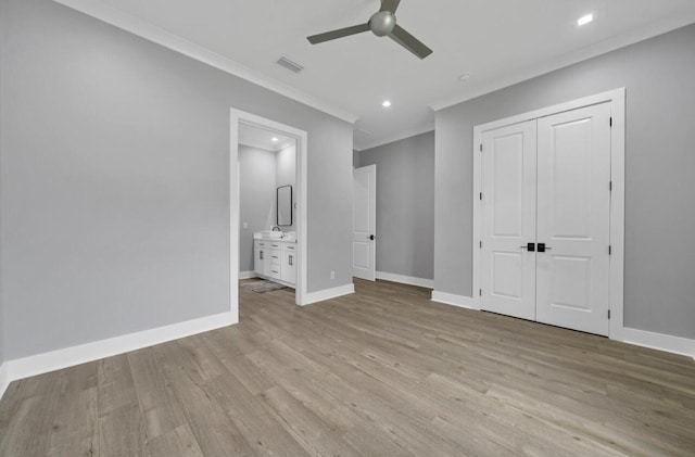 unfurnished bedroom with ensuite bathroom, crown molding, ceiling fan, light wood-type flooring, and a closet