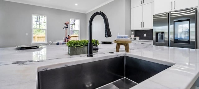 kitchen with decorative backsplash, stainless steel refrigerator with ice dispenser, crown molding, sink, and white cabinets