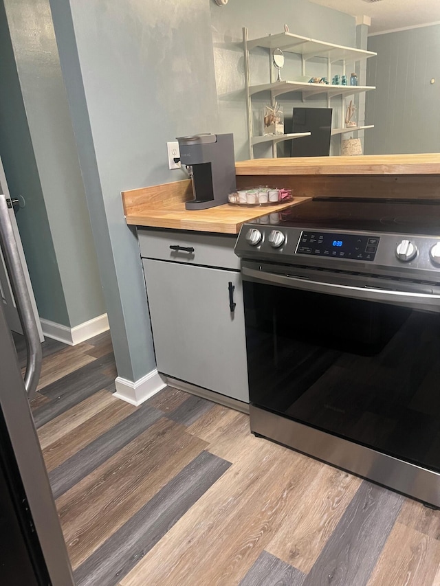 kitchen with butcher block counters, hardwood / wood-style floors, and stainless steel range oven