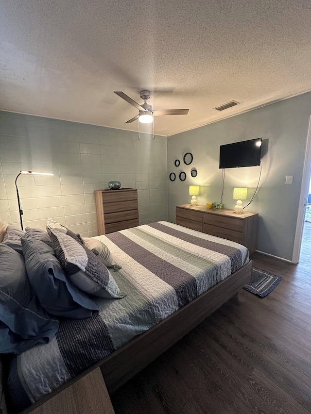 bedroom with ceiling fan, dark wood-type flooring, and a textured ceiling