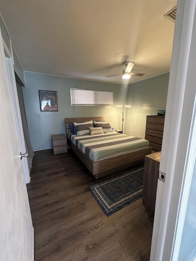 bedroom featuring a textured ceiling, ceiling fan, and dark wood-type flooring