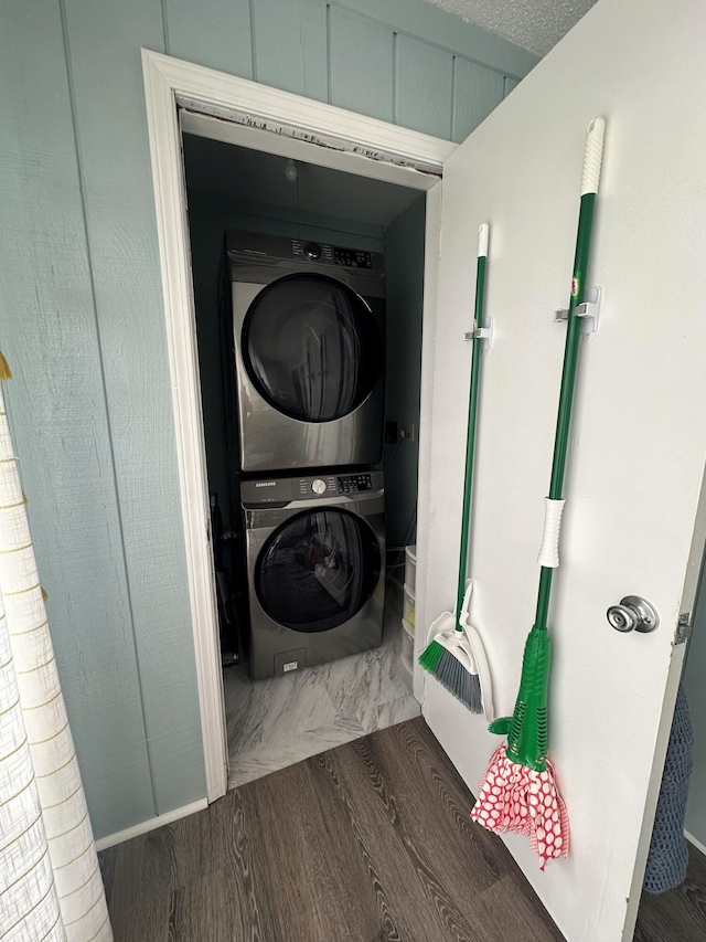 clothes washing area with a textured ceiling, dark hardwood / wood-style flooring, and stacked washer and clothes dryer