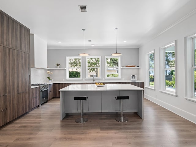 kitchen featuring stainless steel stove, a breakfast bar area, decorative backsplash, and a kitchen island