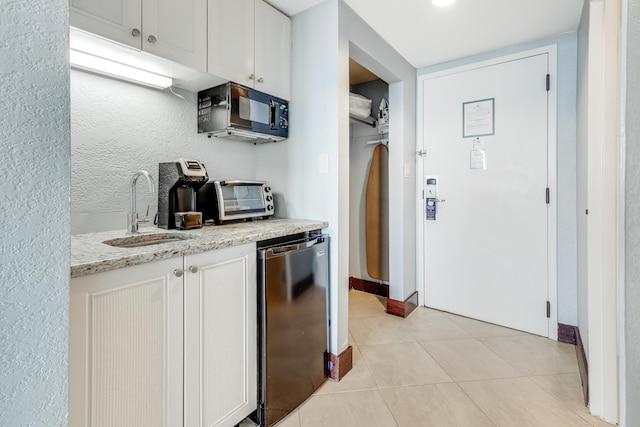 kitchen featuring white cabinets, fridge, sink, and light stone counters