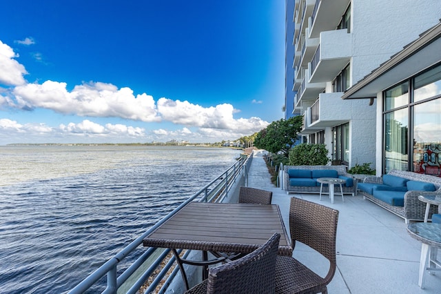 view of patio with a water view, an outdoor living space, and a balcony