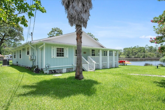 view of front of property featuring cooling unit, a front lawn, and a water view