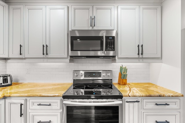 kitchen featuring white cabinets, appliances with stainless steel finishes, and backsplash