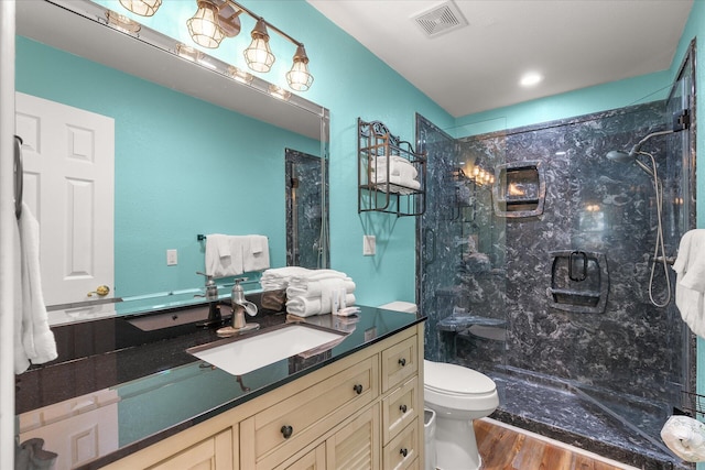 bathroom with hardwood / wood-style floors, a tile shower, vanity, and toilet