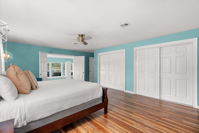 bedroom with hardwood / wood-style floors, two closets, and ceiling fan