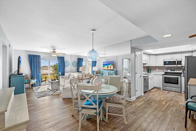 dining room featuring a textured ceiling, sink, ceiling fan with notable chandelier, and light wood-type flooring