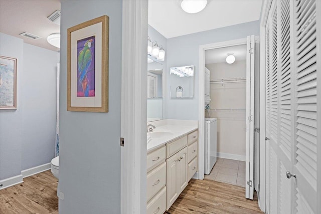 bathroom featuring wood-type flooring, vanity, toilet, and washer and clothes dryer