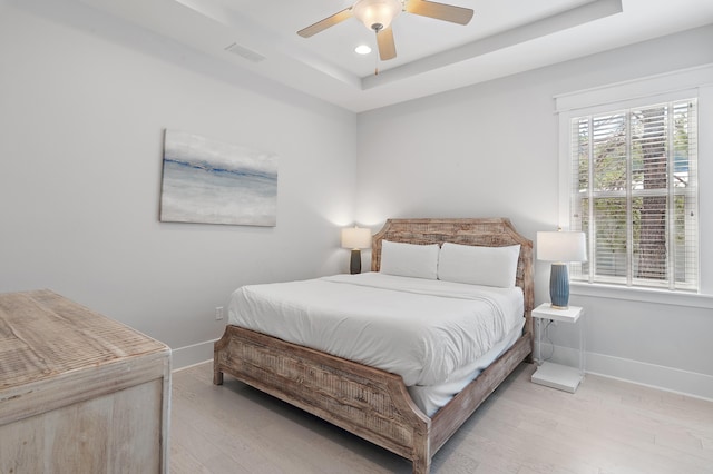 bedroom featuring a raised ceiling, baseboards, and wood finished floors