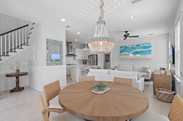 dining space featuring a healthy amount of sunlight, wainscoting, light wood finished floors, and stairs